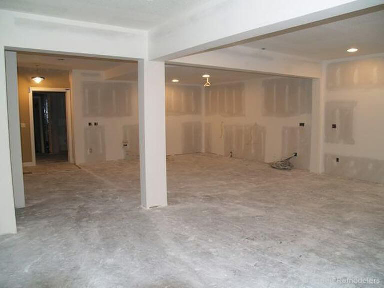 Basement under construction with exposed drywall and concrete floor.